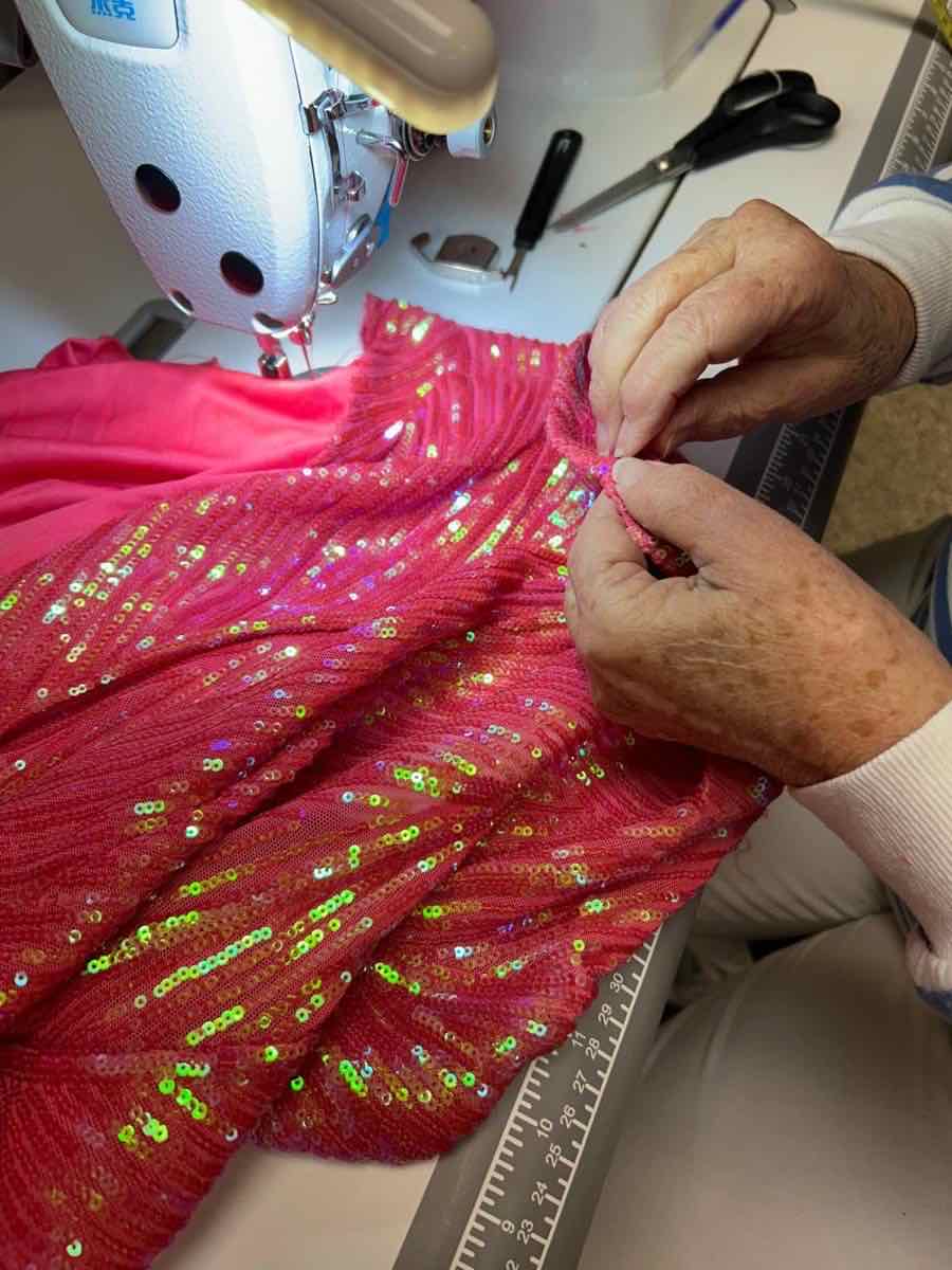 Pink sequin dress being altered at the sewing machine
